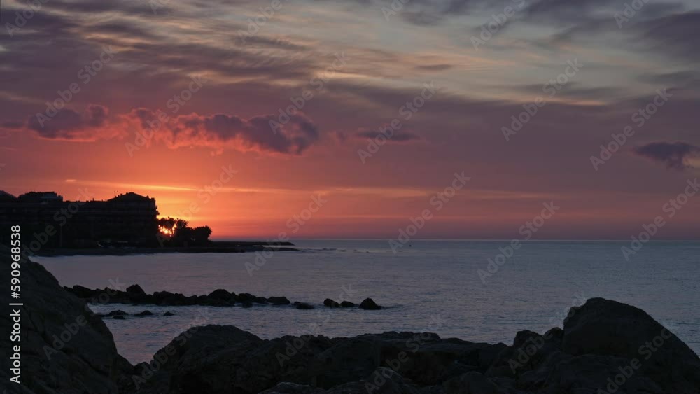 Dramatic timelapse shot of a rocky sea coast during golden hour morning with fast-moving clouds above horizon