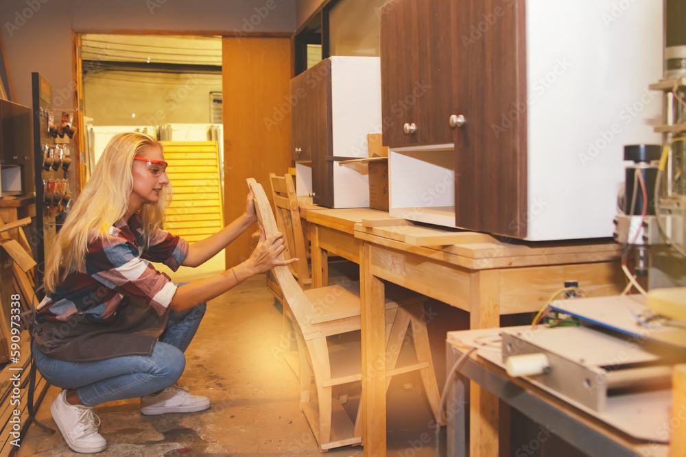 Female carpenter worker woodworking designer furniture small home and office cabinets made of plywood and inspect open and close view beautiful and safe designs prepare to be shipped furniture store.
