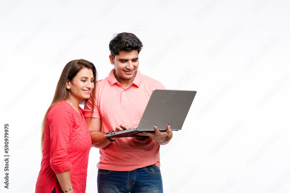 Indian couple using laptop together on white background.