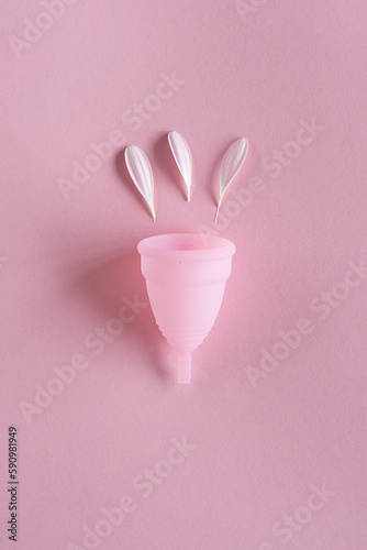 Silicone menstrual cup. Women's health and alternative hygiene. Cup with flower on a pink background. Zero waste alternatives