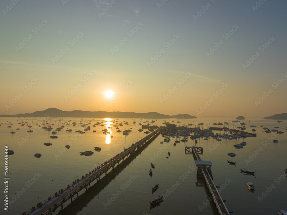 Obraz premium aerial view beautiful sunrise cloud above Chalong pier..Sunrise with sweet yellow color light rays and other atmospheric effects..colorful reflection of sunrise in the sea background.