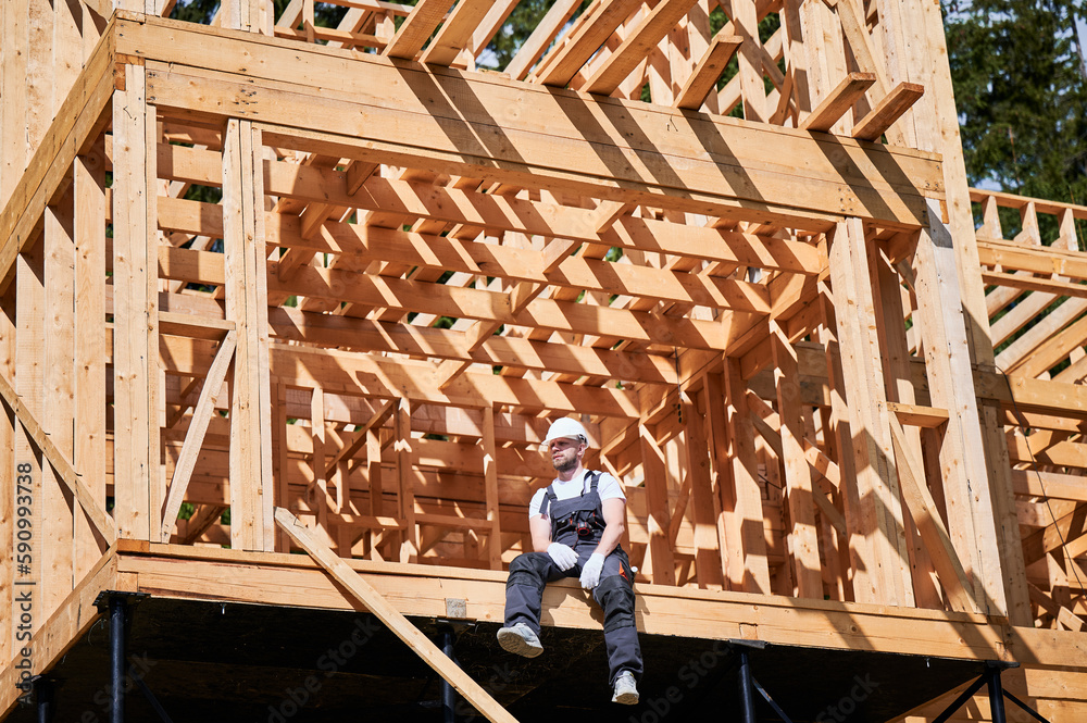 Architect is on construction site of wooden frame twostory house