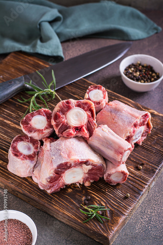 Photos Pieces of raw oxtail and spices for cooking on a wooden board on the table verti