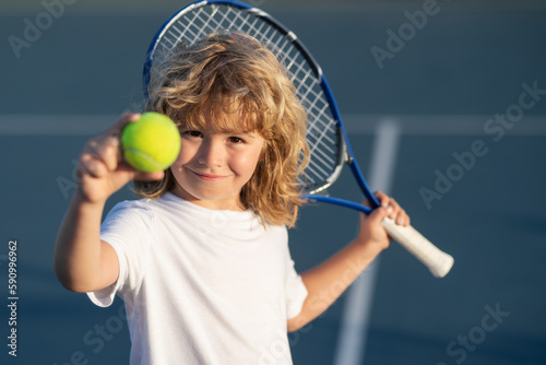 Tennis kid. Child with tennis racket and tennis ball playing on tennis court. © Volodymyr