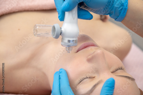 Close up woman patient get hydrogen facial cleansing, hydra peel from cosmetologist hands. Electrolysis antiaging care