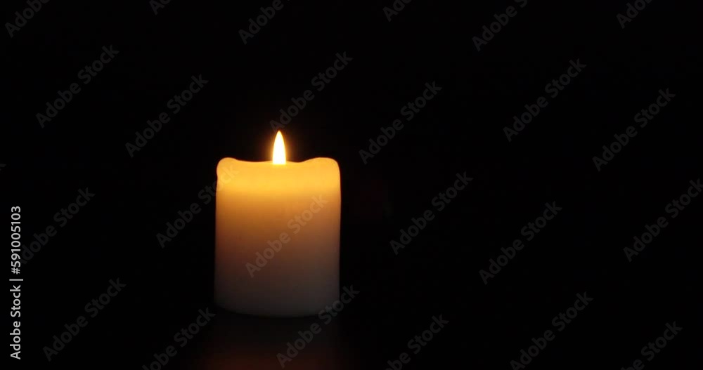 A burning insulated candle on a dark background. Background of grief, memories or celebrations A burning insulated candle on a dark background. Background of grief, memories or celebrations