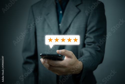 Five Star Customer Service Concept for Satisfaction.Businessman holding mobile smartphone for quality feedback related projects, marketing materials, and branding