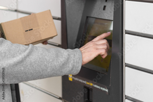Shopping locker inPost with woman hand entering code to open it. Caption: Read the QR code here and pick it up faster.