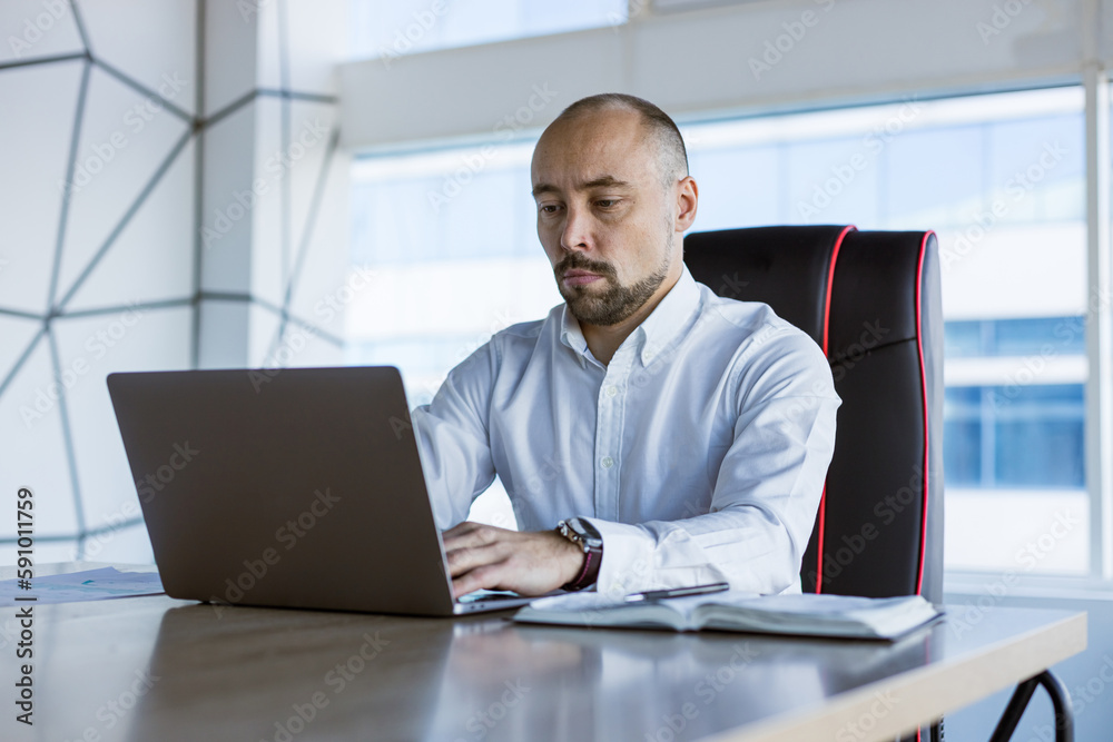 Portrait of a business young successful man in a modern office sitting at a table Portrait of a business young successful man in a modern office sitting at a table