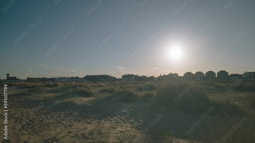 Timelapse shot of city houses in a distance along the beachside in Great Yarmouth, Norfolk, England at sunset. Timelapse shot of city houses in a distance along the beachside in Great Yarmouth, Norfolk, England at sunset.