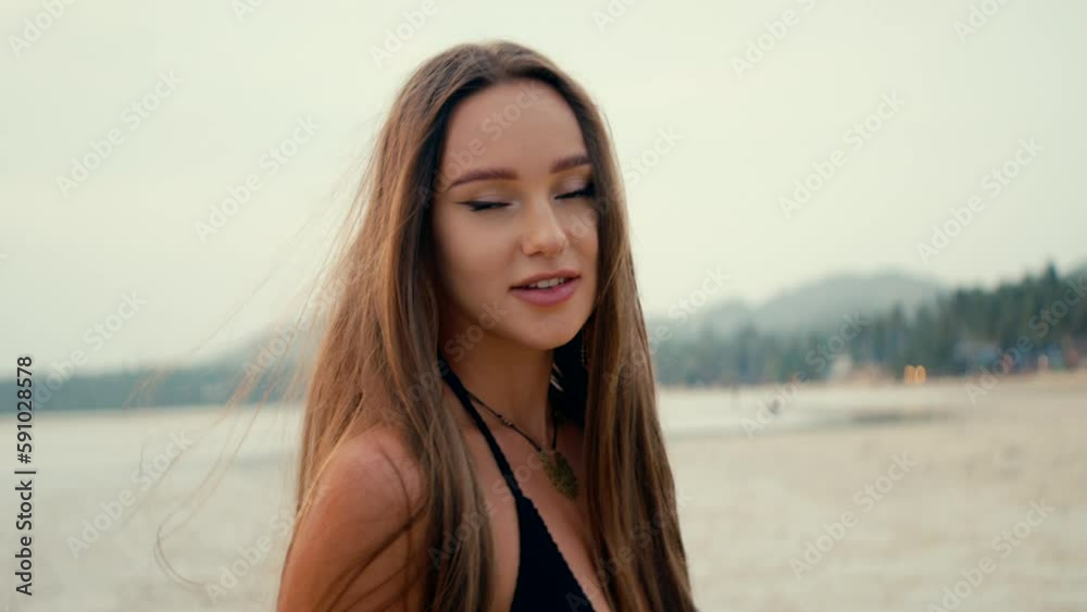Beautiful long-haired girl walks on the beach at sunset. Anamorphic shot Beautiful long-haired girl walks on the beach at sunset. Anamorphic shot