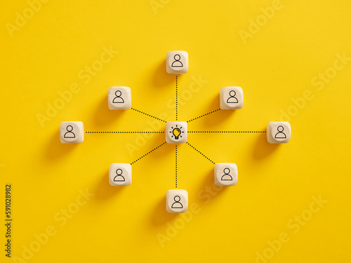 Teamwork and creative idea development. Brainstorming. Creative collaboration in business. Team members connect with idea light bulb symbol on wooden cubes.