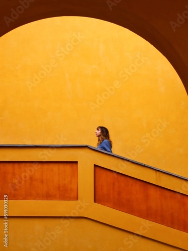 young woman dressed in blue going up on a stairway in a orange building 