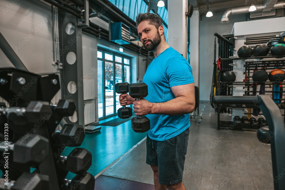 Man working with dumbbells in a sports club