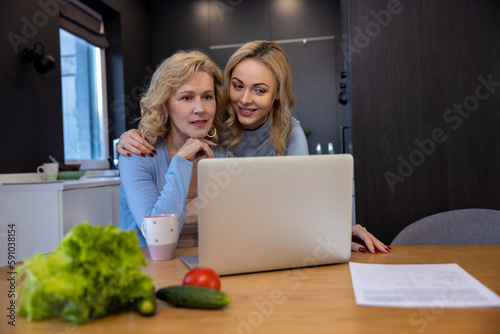 Two women using the portable computer in the kitchen