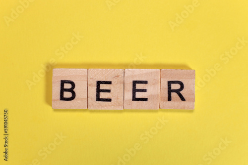 Beer word from wooden letters on yellow background