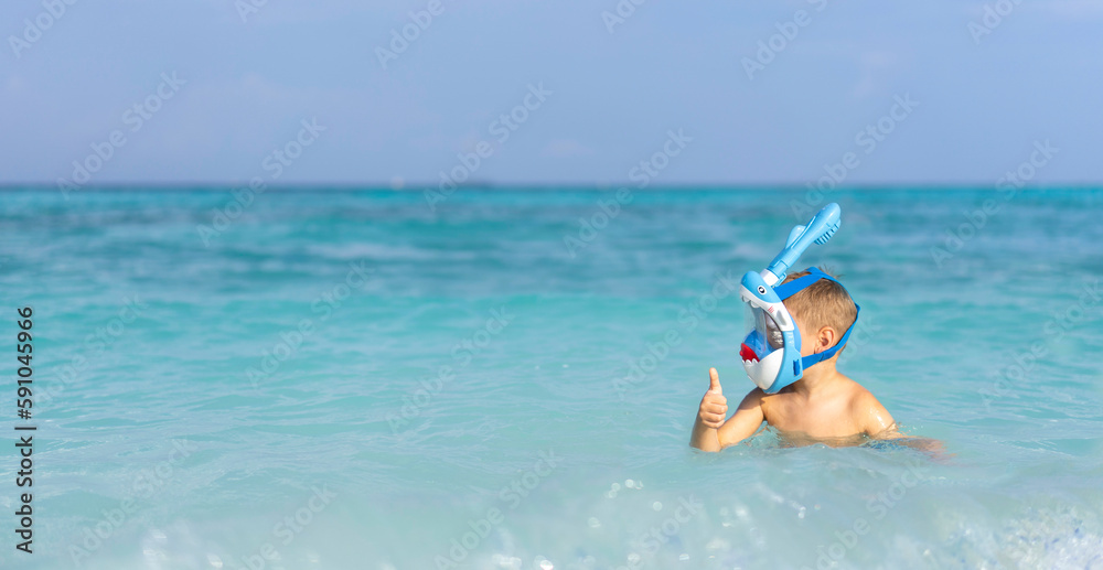 A little boy in a full face mask is snorkeling in the Maldives