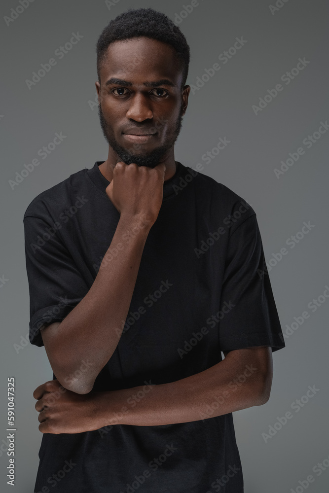 Studio shot of black man with dressed in t shirt posing with his hand under his chin. Studio shot of black man with dressed in t shirt posing with his hand under his chin.