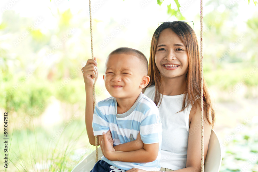 Happy mother and son on the swing in the park Happy mother and son on the swing in the park