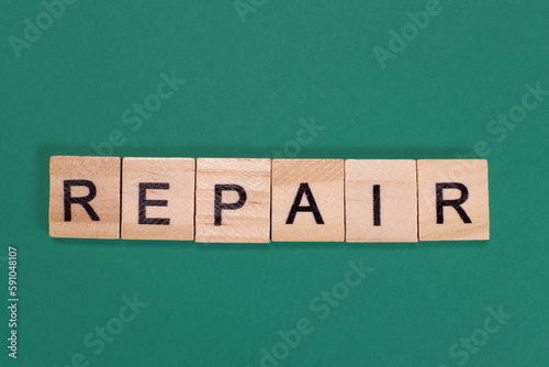 Repair word from wooden letters on green background