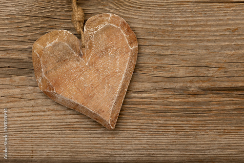 a wooden heart on rustic brown wooden background with free space for text