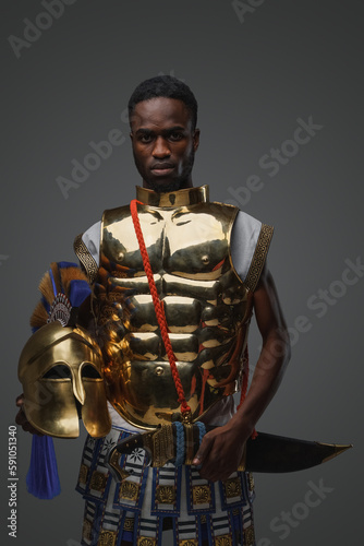 Studio shot of ancient greek warrior of african ethnic dressed in golden armor.