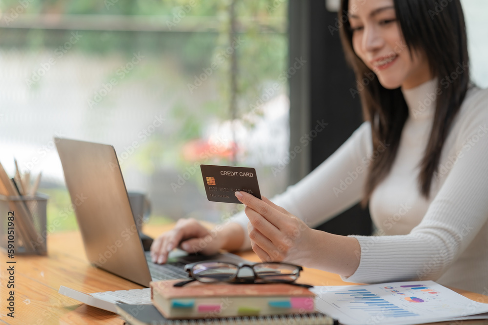 Close-up hand of a woman using a credit card for online shopping payment with a laptop computer. Technology and Business Concept. Close-up hand of a woman using a credit card for online shopping payment with a laptop computer. Technology and Business Concept.