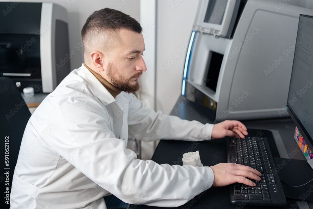 Digital dentistry. Man working with digital scan in modern dentistry. Dental prosthesis on a computer scanner. The dental image is displayed on the computer screen.