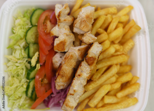 Lunch box with Greek kalamaki dish prepared with souvlaki meat, fries and fresh vegetables.
