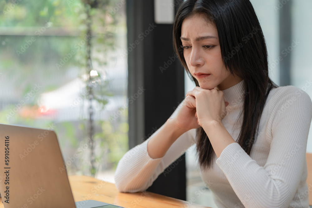 Concerned female worker looking at laptop screen suspiciously, thinking about problem-solving, reading ambiguous emails or negative news. Concept of focus and concentration. Concerned female worker looking at laptop screen suspiciously, thinking about problem-solving, reading ambiguous emails or negative news. Concept of focus and concentration.