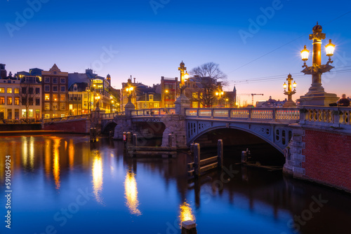 Blue bridge  Amsterdam  Netherlands. Blauwbrug. Evening cityscape. Blue sky and city lights.  Dutch canals. Reflections on the surface of the water. Photography for design and wallpaper.