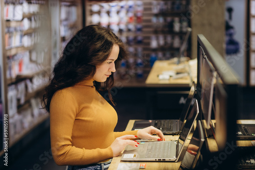 Side view of female selecting a laptop in a tech store.