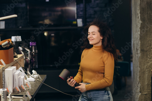 Woman buying hair dryer and straightener in tech store