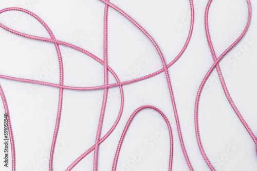 Poplątana  różowa linka tworząca wzór na białym tle