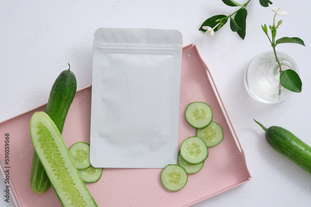 A mask sheet decorated on pink tray with Cucumber slices, a flower vase beside. The cooling and anti-inflammatory effect of Cucumber (Cucumis sativus) may help ease pain, redness, and irritation A mask sheet decorated on pink tray with Cucumber slices, a flower vase beside. The cooling and anti-inflammatory effect of Cucumber (Cucumis sativus) may help ease pain, redness, and irritation