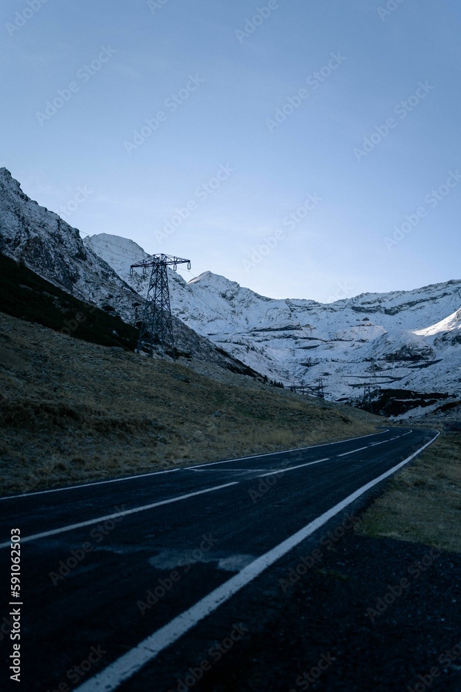 Vertical shot of an empty asphalt road against the snowy hills