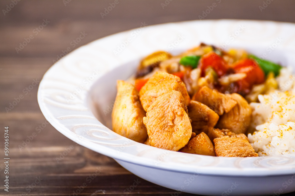 Asian food - chicken nuggets, rice, stir fried vegetables, soy sauce and mushrooms on wooden table 