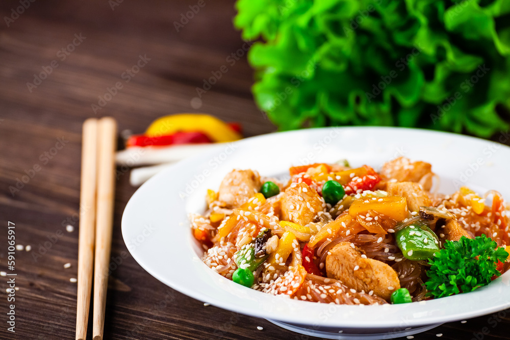 Asian food - chicken nuggets, rice, stir fried vegetables, soy sauce and mushrooms on wooden table 