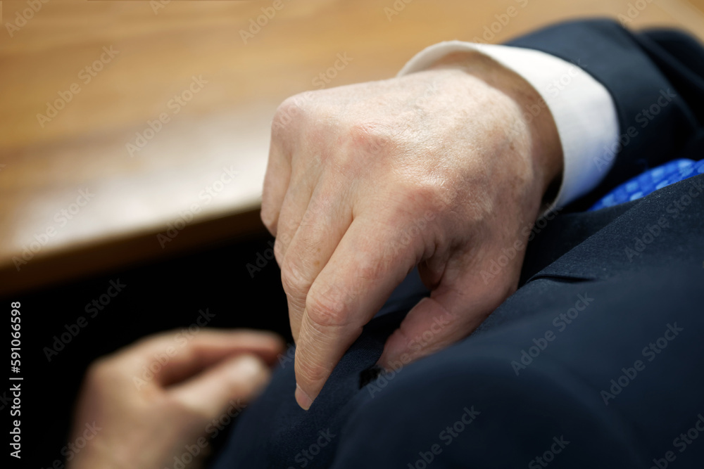 Adult man in a white shirt and a stylish suit checks the contents of the breast chest pocket of his jacket. View from above. Selective focus.