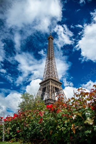 Vertical low angle shot of the Eiffel Tower against a blue cloudy sky in Paris, France
