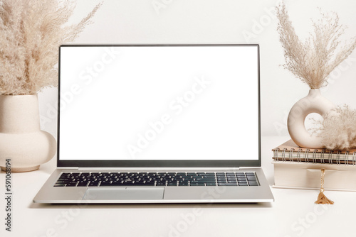 Mockup laptop with white screen on the table with vase, pampas grass, book and notepad. Aesthetic background for study, cozy home office, website promotion, social media