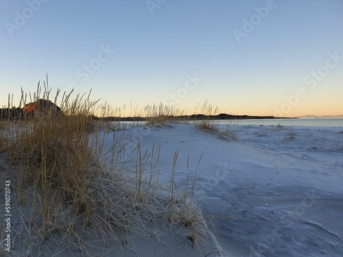 Lakeshore covered in snow at sunset with orange and blue sky in the background