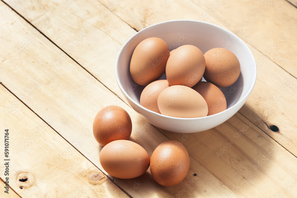 Chicken eggs in white bowl on a wood table Chicken eggs in white bowl on a wood table