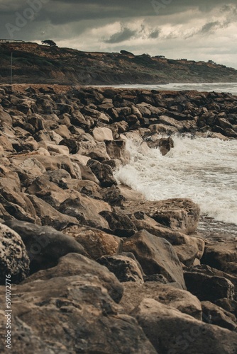 Vertical shot of the rocky shore on a cloudy day.