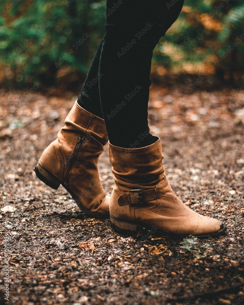 Vertical shot of a female in brown boots walking in a forest Vertical shot of a female in brown boots walking in a forest