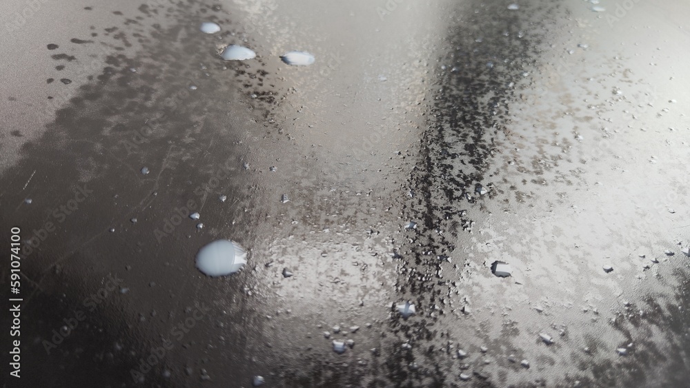 Water drops on a black plastic. Surface with wet background. Abstract texture and pattern full of water. Raindrops of rain for overlaying on window with partial focus. Concept of autumn weather