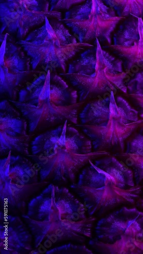 A close-up of rotating pineapple peel with blue and purple lighting in a vertical video.