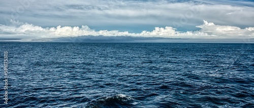 Panoramic shot of a beautiful dark blue sea with cloudy sky in the background