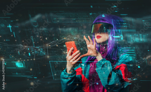 Concept of stylish woman in VR glasses with smartphone and future interface on dark background photo