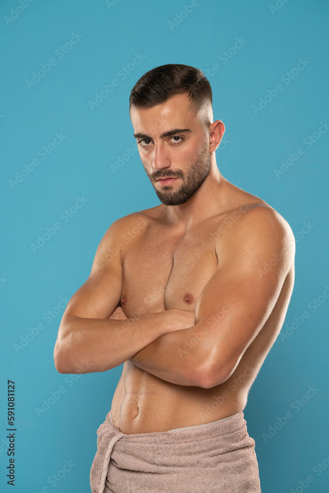 Shirtless young man with folded arms on a blue background Shirtless young man with folded arms on a blue background